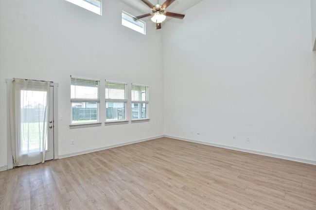 Unfurnished room with a towering ceiling, a ceiling fan, light wood-type flooring, and plenty of natural light | Image 4