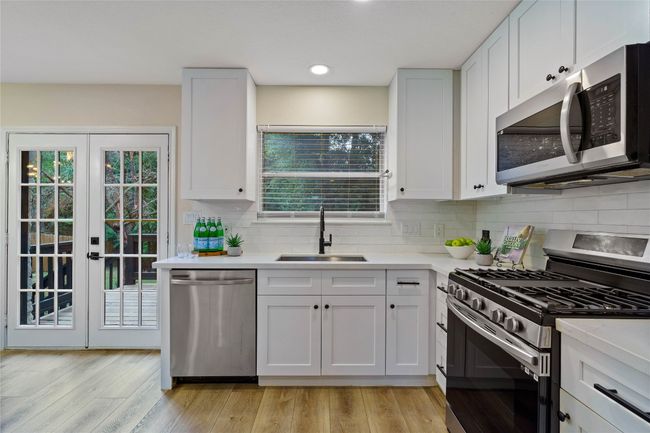 Kitchen featuring stainless steel appliances, a healthy amount of sunlight, light countertops, and a sink | Image 15