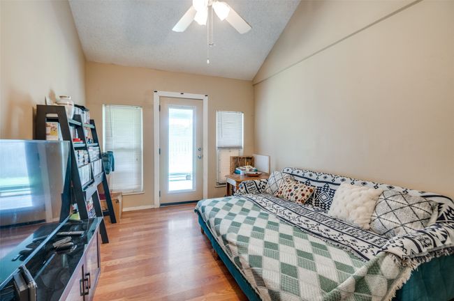 Bedroom featuring light wood finished floors, lofted ceiling, a fireplace, and ceiling fan | Image 21