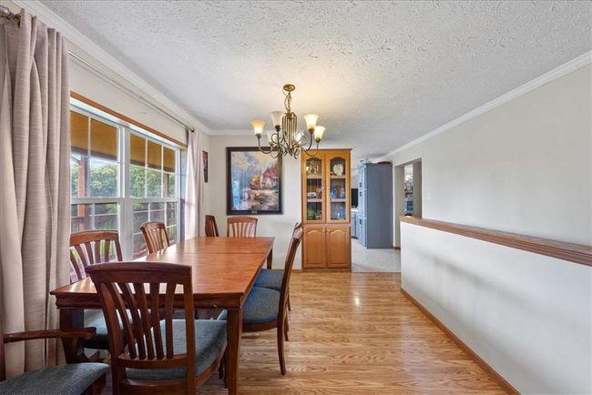 Dining room featuring crown molding, baseboards, a chandelier, a textured ceiling, and light wood-style flooring | Image 14