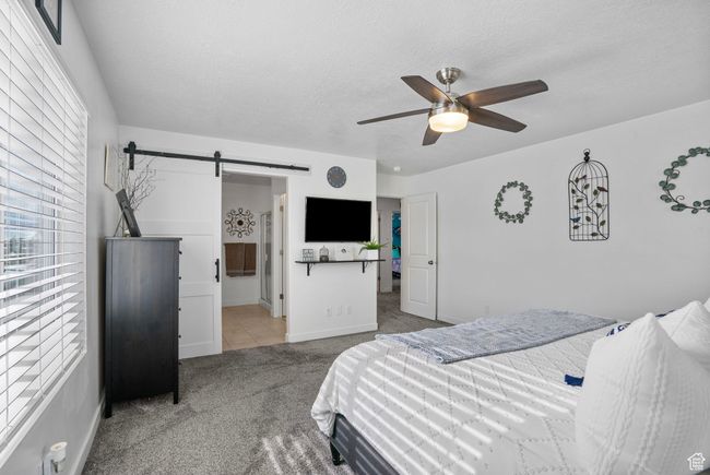 Bedroom featuring a barn door, carpet, tile patterned floors, baseboards, and a textured ceiling | Image 12