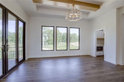 Unfurnished room featuring dark hardwood / wood-style flooring, a wealth of natural light, an inviting chandelier, and beam ceiling | Image 3