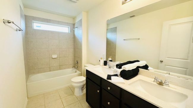 Bathroom with double vanity, tile patterned floors, and tub / shower combination | Image 31