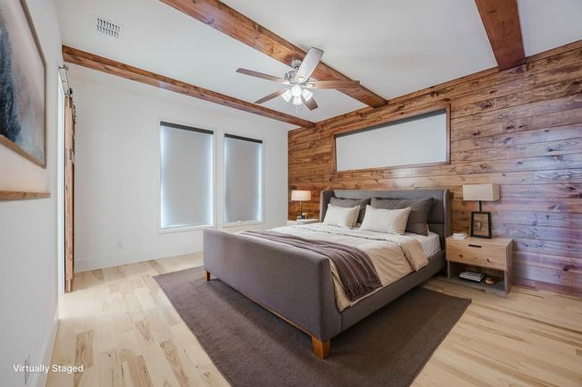 Bedroom featuring wooden walls, beamed ceiling, light wood-style flooring, and ceiling fan | Image 16