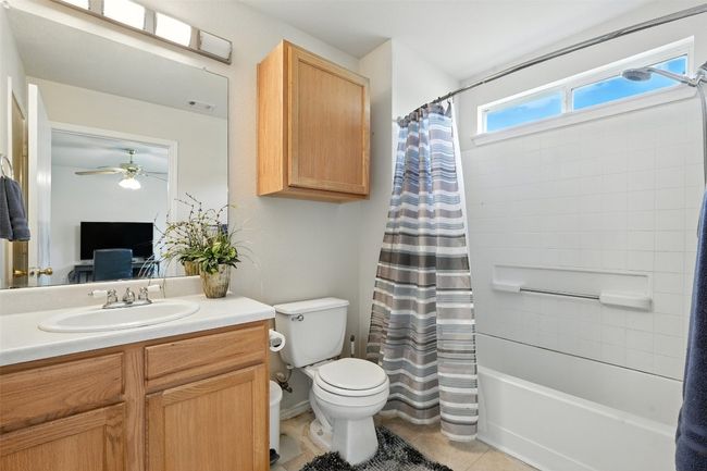 Full bathroom with shower / bathtub combination with curtain, vanity, light tile patterned flooring, and a ceiling fan | Image 19