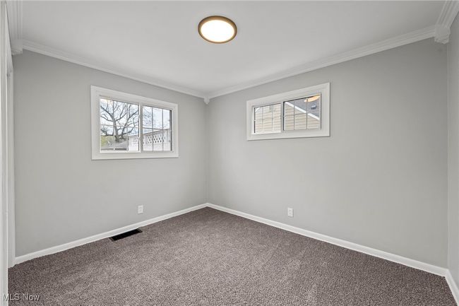 Carpeted empty room with ornamental molding, visible vents, and baseboards | Image 20