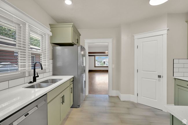 Kitchen with green cabinets, appliances with stainless steel finishes, a sink, and plenty of natural light | Image 13