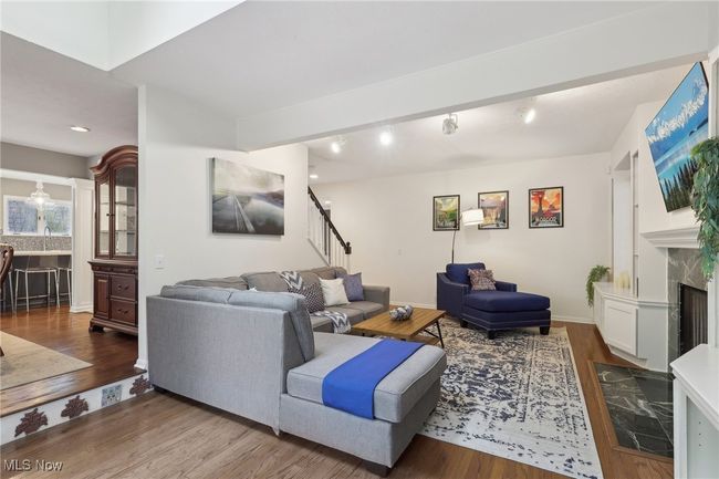 Living room with recessed lighting, wood finished floors, a high end fireplace, baseboards, and stairway | Image 12
