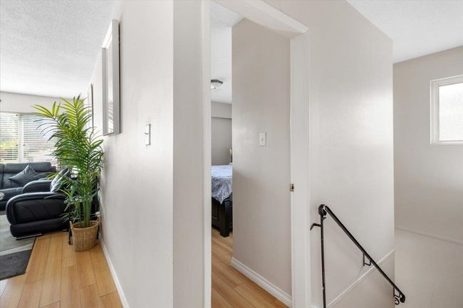 Hall featuring an upstairs landing, light wood-style floors, baseboards, and a textured ceiling | Image 15