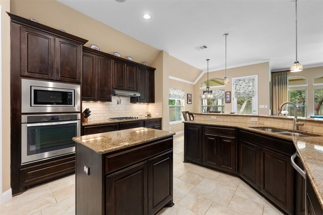Kitchen featuring appliances with stainless steel finishes, under cabinet range hood, tasteful backsplash, plenty of natural light, and vaulted ceiling | Image 19