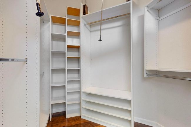 Walk in closet with dark wood-style flooring: custom shelving | Image 22