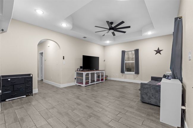 Living room with ceiling fan, arched walkways, recessed lighting, a tray ceiling, and wood finished floors | Image 11