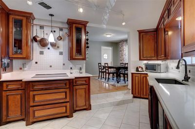 Kitchen featuring decorative backsplash, sink, light wood-type flooring, and hanging light fixtures | Image 3