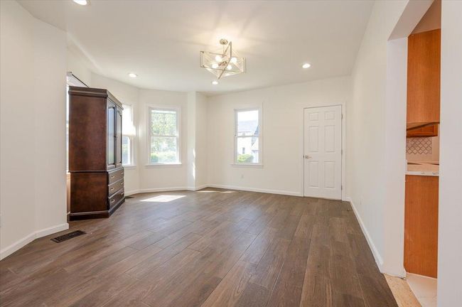 Empty room featuring an inviting chandelier, dark wood finished floors, visible vents, and recessed lighting | Image 5