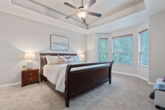 Bedroom with bar window, carpet flooring, a tray ceiling, baseboards, and a ceiling fan | Image 19