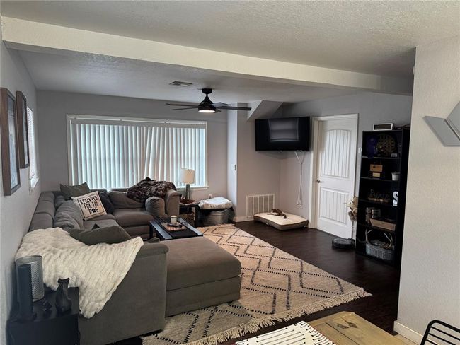 Living room featuring ceiling fan, dark hardwood / wood-style floors, and a textured ceiling | Image 7