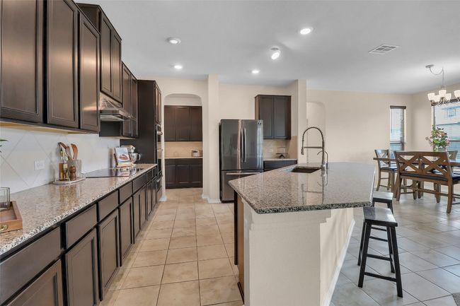 Kitchen with a sink, appliances with stainless steel finishes, arched walkways, under cabinet range hood, and a breakfast bar area | Image 9