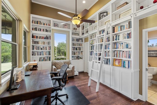 Office featuring ceiling fan, crown molding, built in shelves, dark wood-style floors, and recessed lighting | Image 9