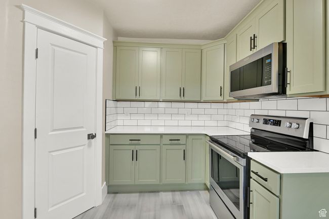 Kitchen featuring green cabinetry, appliances with stainless steel finishes, light countertops, and backsplash | Image 10