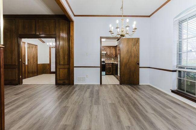 Unfurnished dining area featuring light wood-type flooring, ornamental molding, visible vents, and a notable chandelier | Image 6