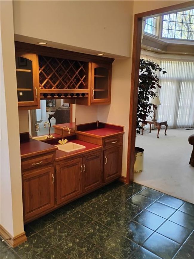 Bar with dark carpet, wet bar, a sink, and baseboards | Image 26