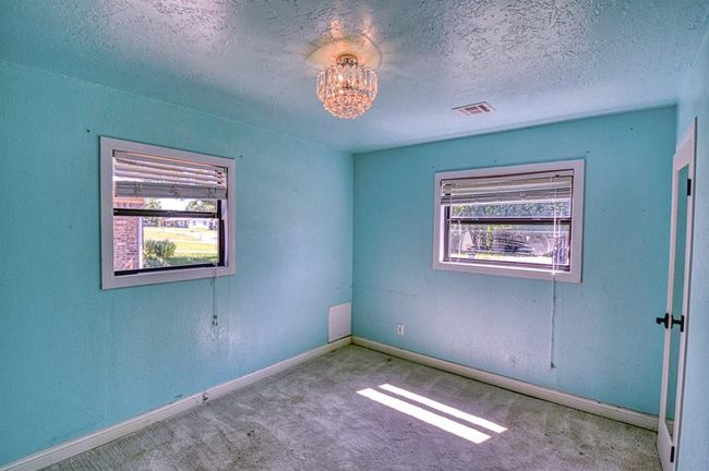 Spare room featuring carpet, a textured ceiling, baseboards, and a chandelier | Image 17