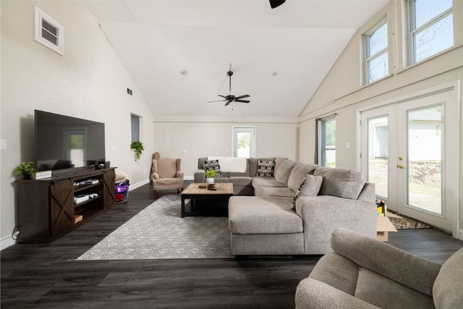 Living room with high vaulted ceiling, dark wood-style flooring, baseboards, and a ceiling fan | Image 21
