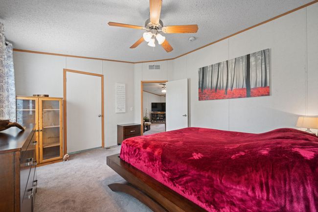 Primary Bedroom featuring crown molding, carpet flooring, a textured ceiling, and a ceiling fan | Image 18