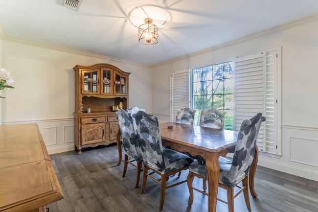 Dining area featuring crown molding, dark wood-style flooring, wainscoting, and a decorative wall | Image 10