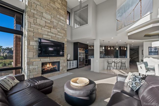 Living room featuring carpet flooring, a fireplace, and a towering ceiling | Image 48
