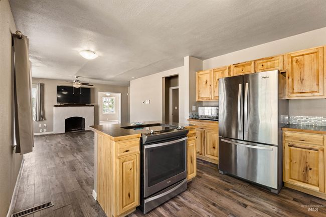 Kitchen with stainless steel appliances, a textured ceiling, a fireplace, dark wood-type flooring, and dark countertops | Image 15