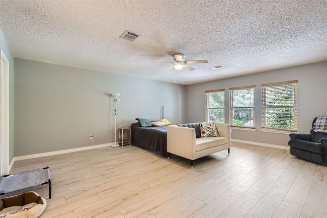 Bedroom with a textured ceiling, baseboards, light wood finished floors, and a ceiling fan | Image 14