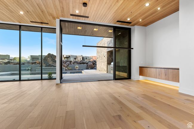Empty room with expansive windows, hardwood / wood-style floors, a healthy amount of sunlight, and wooden ceiling | Image 28