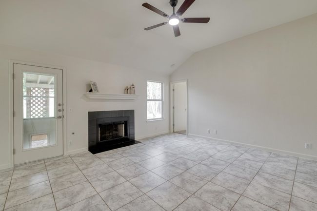 Unfurnished living room with plenty of natural light, a ceiling fan, lofted ceiling, and a fireplace | Image 6