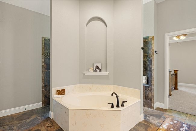 Bathroom featuring a bath, stone tile floors, and tiled shower | Image 25