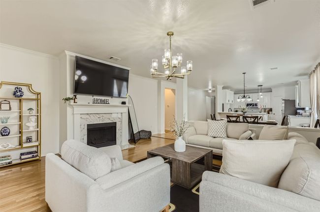 Living room with a chandelier, a premium fireplace, light wood finished floors, and crown molding | Image 6