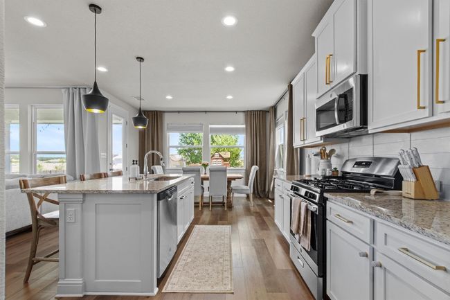 Kitchen with appliances with stainless steel finishes, an island with sink, light stone countertops, dark wood-style flooring, and recessed lighting | Image 15