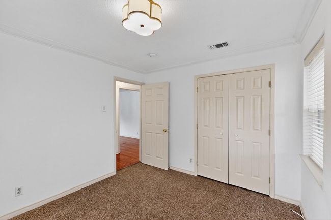 Unfurnished bedroom with carpet flooring, crown molding, a closet, and multiple windows | Image 30