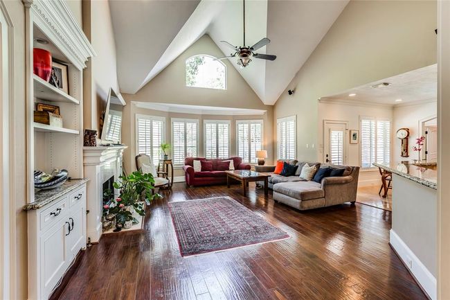 Sunning Living room with high vaulted ceiling, built ins with granite tops, gas fire, hardwood floor & plantation shutters | Image 10