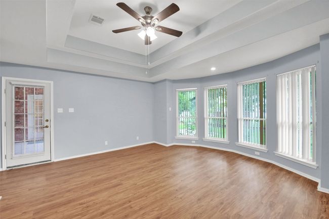 Master bedroom \ with a tray ceiling, ceiling fan, and vinyl plank floors | Image 28