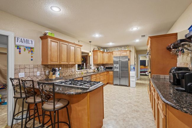 Kitchen with stainless steel appliances, a peninsula, a sink, visible vents, and decorative backsplash | Image 8