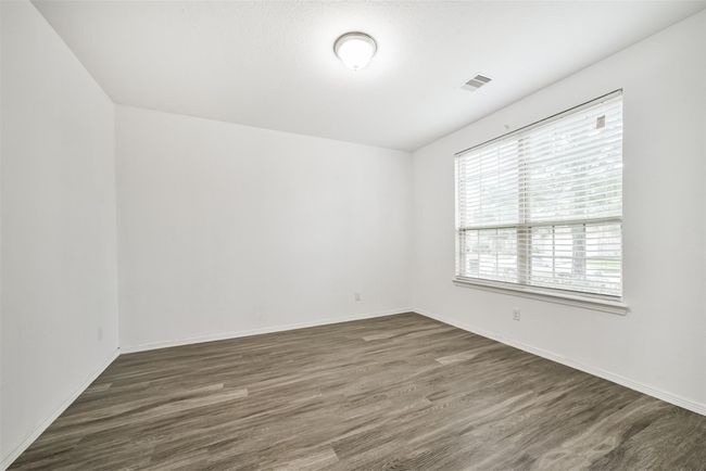 Bright, spacious study with clean white walls and wood-look flooring. Features a large window with blinds, offering ample natural light. Ideal for a bedroom or home office. | Image 8
