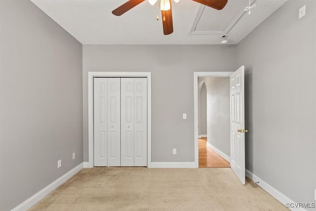 Unfurnished bedroom with attic access, light colored carpet, a closet, and baseboards | Image 36