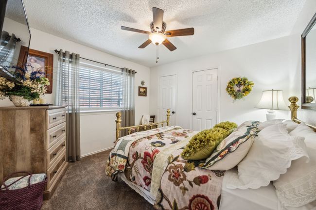 Bedroom featuring a textured ceiling, dark colored carpet, ceiling fan, two closets, and baseboards | Image 6