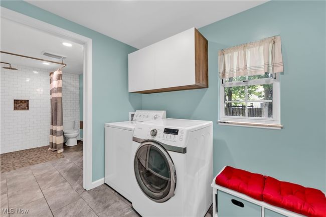 CONVENIENT LAUNDRY ROOM WITH TILED FLOORING - CABINETS AND WASHER AND DRYER | Image 15