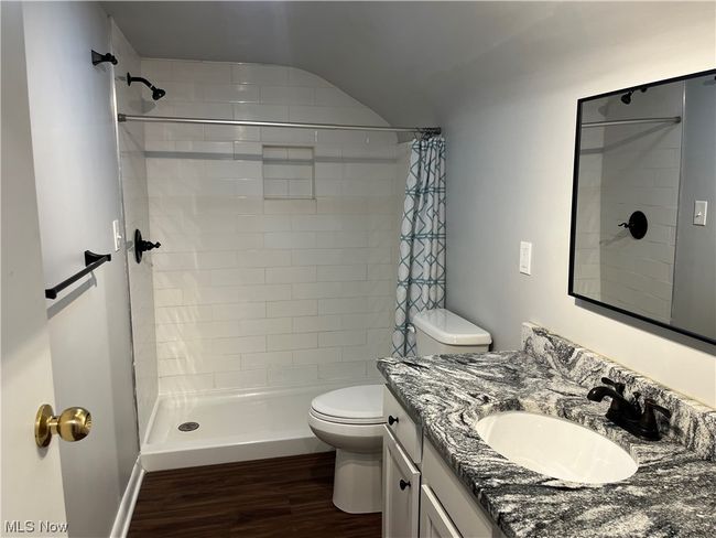 Bathroom with hardwood / wood-style flooring, vaulted ceiling, large vanity, walk in shower, and toilet | Image 24