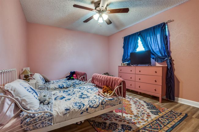 Bedroom with a textured ceiling, ceiling fan, wood finished floors, and radiator heating unit | Image 18