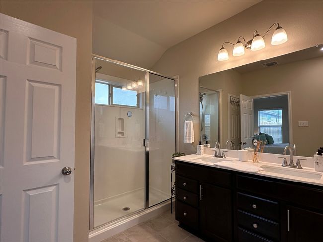 Bathroom with a shower stall, double vanity, tile patterned flooring, ensuite bath, and lofted ceiling | Image 33