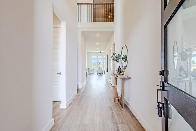 Step through the modern glass door into a light-filled entryway with soaring ceilings, clean lines, and a view that draws your eyes straight to the back windows and water beyond. | Image 8