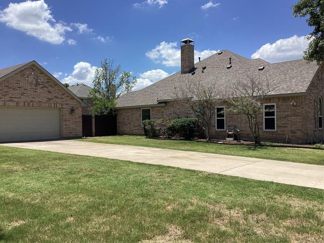 View of front facade featuring a front lawn, brick siding, a chimney, concrete driveway, and a shingled roof | Image 33
